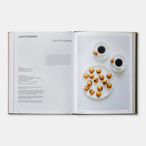 Open book showing a page with 'Lady's Kisses' and 'Baci di Dama', featuring a plate of cookies and two cups of coffee.