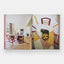 Book open to a page showing a dining room with red chairs and a geometric abstract painting.