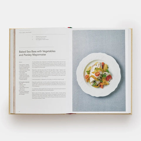 Open cookbook showing a recipe for Baked Sea Bass with Vegetables and Parsley Mayonnaise.