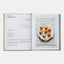 Open cookbook showing a recipe for Sicilian croquettes with a plate of food on a white background.