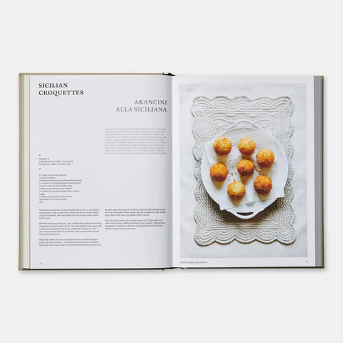 Open cookbook showing a recipe for Sicilian croquettes with a plate of food on a white background.
