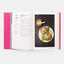 Open cookbook showing a page with a recipe and a photo of tacos on a plate.