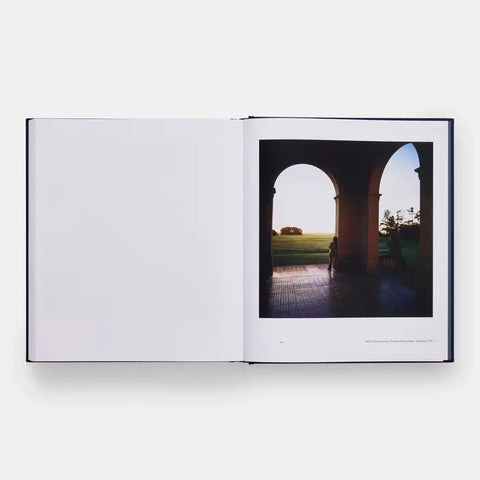 Open book with a photograph of a person sitting under arches looking out onto a field.