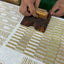 A close-up of a person's hands hand blocking a patterned textile. 