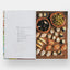 Open book showing a page with text and an illustration of food on a wooden board.