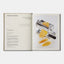 Open book showing a pasta maker with fresh egg pasta on a white background