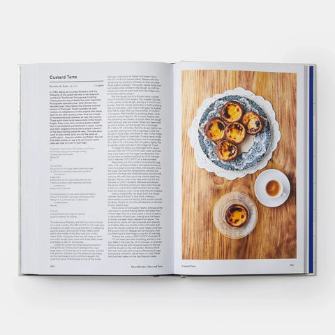 Open cookbook showing a page with custard tarts on a wooden board